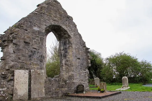 a stone archway with trees and grass