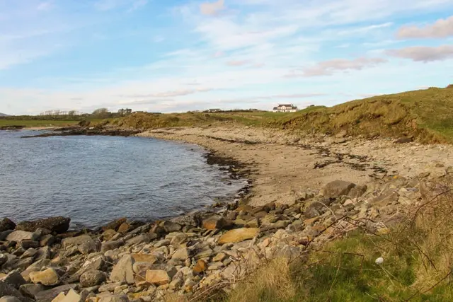 a rocky beach with a house in the distance