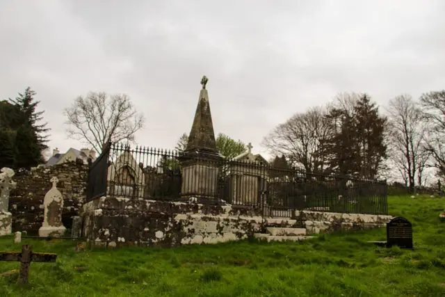 a cemetery with a fence and a church in the background