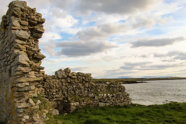 a stone wall next to a body of water