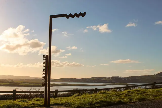 a pole with a sign on it by a body of water