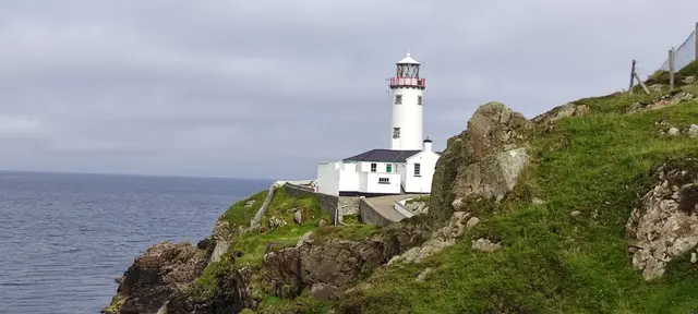 a lighthouse on a hill by the water