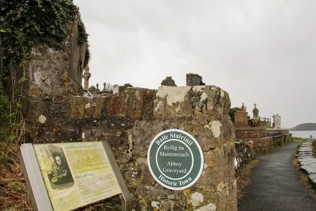 a stone wall with a sign on it and a stone wall with a stone wall and a road