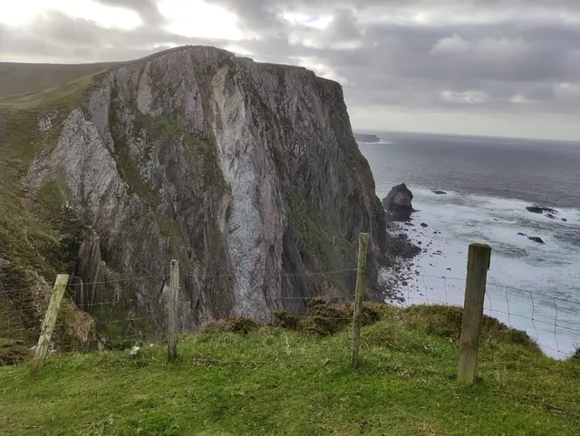 a cliff with a fence and a body of water below