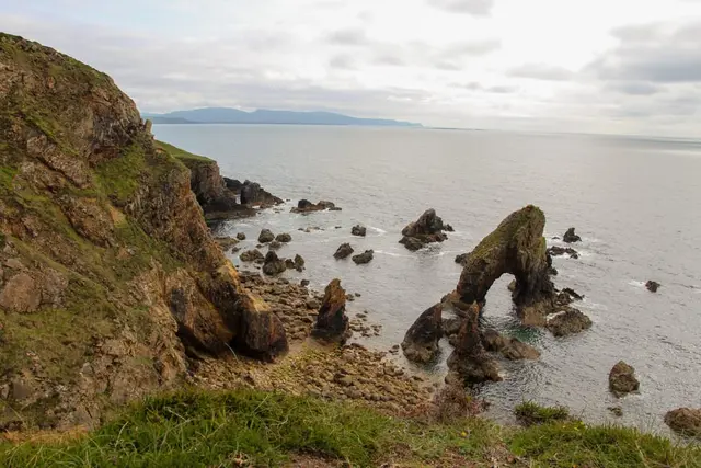 a rocky beach with a body of water in the background