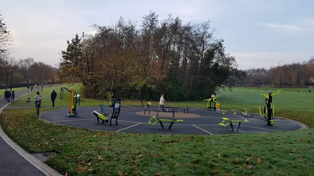 a group of people walking around a park with benches